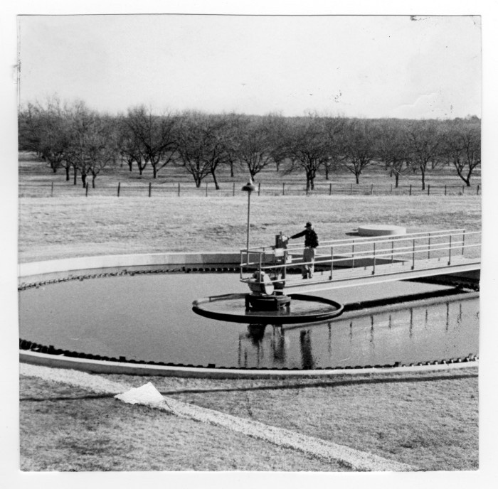 Operators working on a circular clarifier — wastewater treatment, decades ago